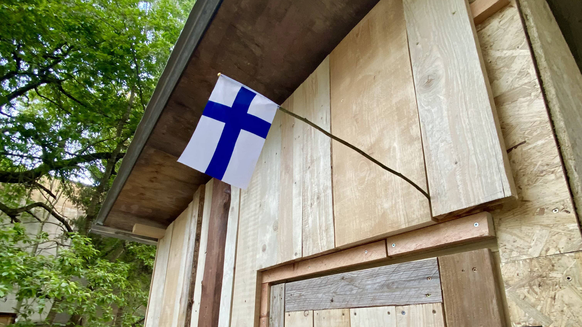 Suomen lippu puisen rakennuksen oven päällä