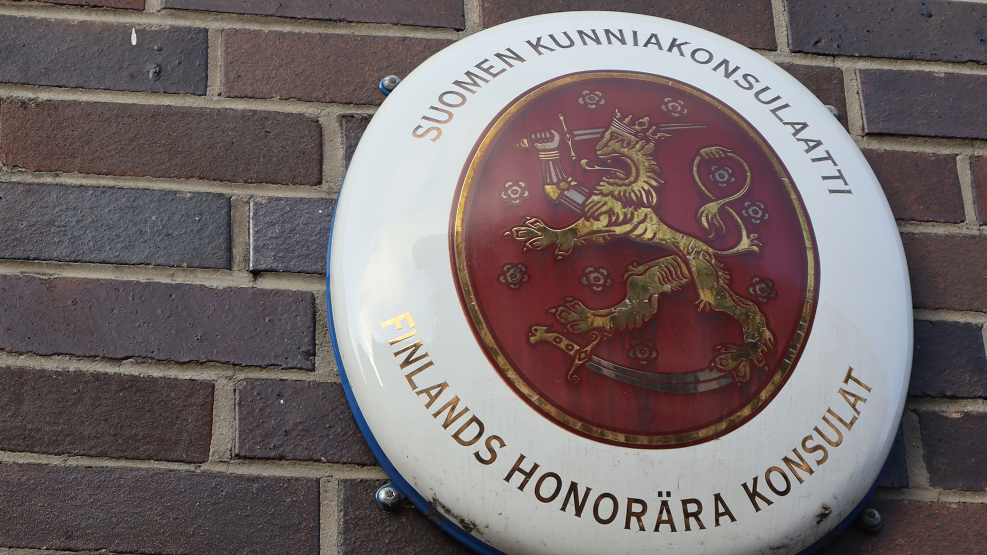 Suomen kunniakonsulaatin vaakunakilpi tiiliseinässä
