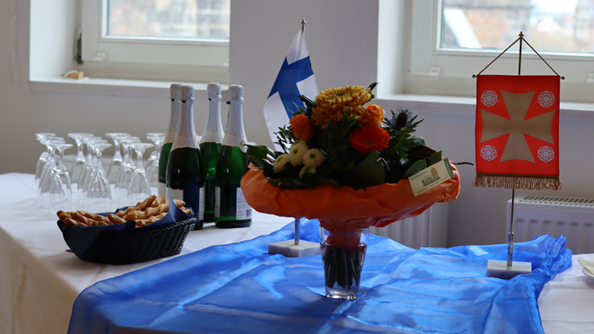 kuohuviinilaseja, kukkakimppu, kirkkolippu pöydällä