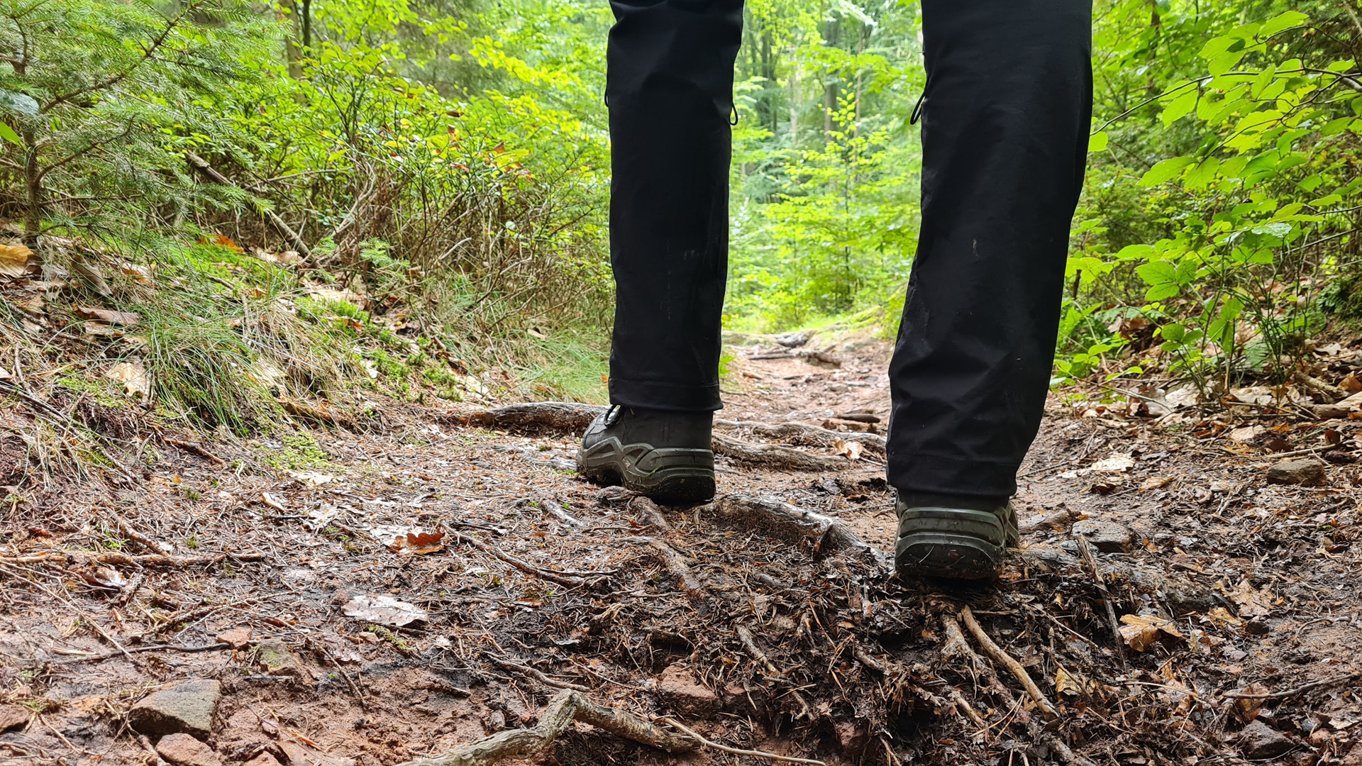 vaeltajan jalat metsäpolulla takaapäin kuvattuna