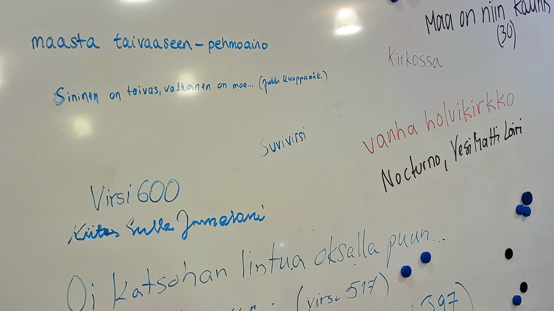 virsien ja laulujen nimiä kirjoitettu valkotaululle