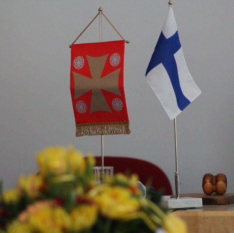Suomalaisen kirkollisen työn keskuksen vuosikokous Suomen kirkon viiri ja Suomen lippu kokouspöydällä
